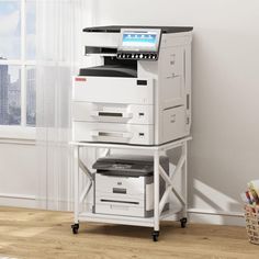 a white and black printer sitting on top of a table next to a large window