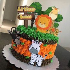 a cake decorated with animals and trees on top of a table next to a sign