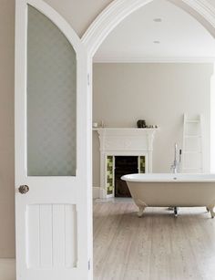 an open door leading to a bathroom with a bathtub and fireplace