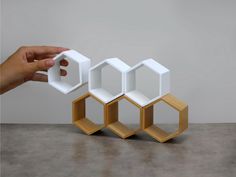 a hand is holding an object in front of three hexagonal objects