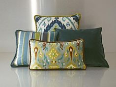 three decorative pillows sitting next to each other on a white countertop in front of a wall