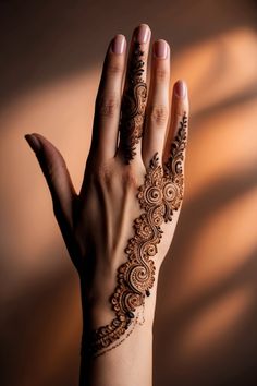 a woman's hand with henna tattoos on her left arm and fingers, showing the intricate design