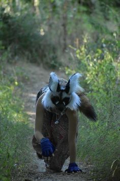 a woman in blue gloves is walking down a path with a dog on her back