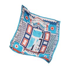 a blue and red pillow with an ornate design on the front, sitting against a white background