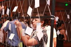 a group of people standing next to each other in front of a wall with notes on it