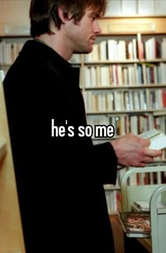 a man standing in front of a bookshelf holding a piece of paper with the words he's some on it