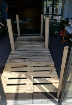 a wooden walkway made out of pallets in front of a building