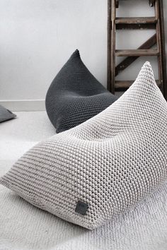 two pillows sitting on top of a bed next to a chair