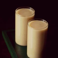 two glasses filled with liquid sitting on top of a green tray