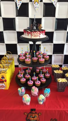 a table topped with lots of cupcakes covered in frosting and toppings