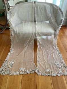 a white chair covered in sheer fabric on top of a wooden floor