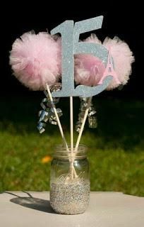 a mason jar filled with pink and silver flowers next to a number 15 sign on top of a table