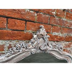 an ornate mirror on the side of a brick wall