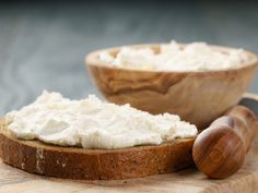 a bowl of cottage cheese next to a knife on a cutting board