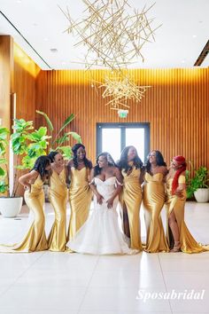 a group of women standing next to each other in front of a window wearing gold dresses