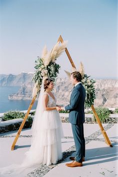 a bride and groom standing in front of an arch decorated with pamodia flowers