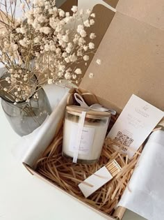 an open box with some candles and papers in it next to a vase filled with flowers