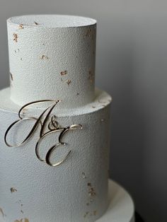 a three tiered white wedding cake with gold foil on top and monogrammed initials