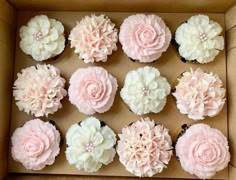 a box filled with cupcakes covered in pink and white frosting flowers on top of each one