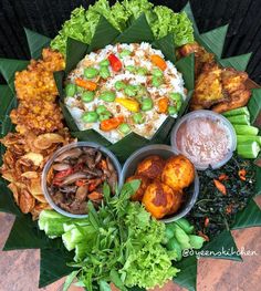 an assortment of food is displayed on a leafy platter with sauces and dipping sauces