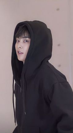 a young man in a black hoodie looking at the camera