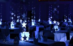 a room filled with tables covered in white tablecloths and star shaped centerpieces