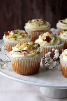 cupcakes with white frosting and flowers on a plate