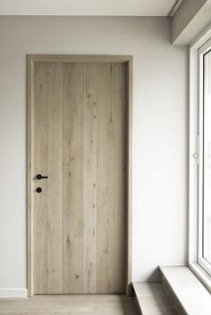 an empty room with a wooden door and window sill on the wall, next to a bench