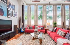 a living room with red couches and pictures hanging on the wall above the fireplace