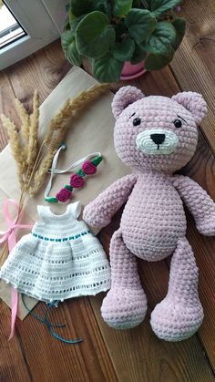 two crocheted teddy bears sitting next to each other on a wooden floor near a potted plant