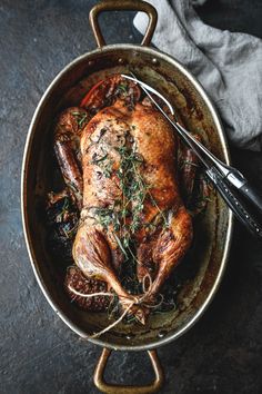 a roasting pan with a whole chicken in it and a serving utensil