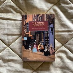 a book about the female detective sitting on top of a white bed sheet with people walking around it