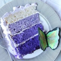 a slice of cake with purple and white frosting on a plate next to a butterfly