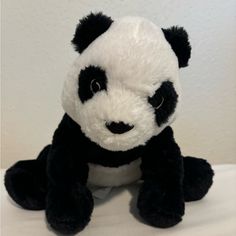 a black and white stuffed panda bear sitting down