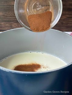 a pot filled with milk and spices on top of a wooden table