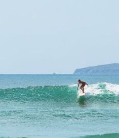 a man riding a wave on top of a surfboard in the middle of the ocean