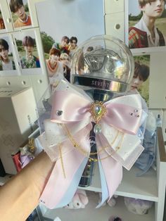 a hand holding a clear ball with a pink bow on it and several pictures behind it