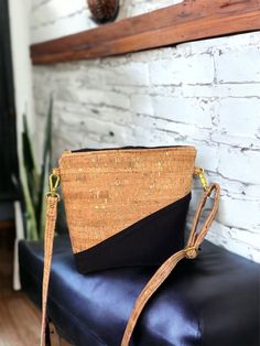 a black and tan purse sitting on top of a leather bench next to a brick wall