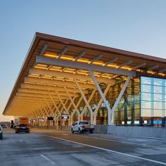 an airport terminal with cars parked in front of it