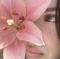 a close up of a woman's face with a pink flower in her hair