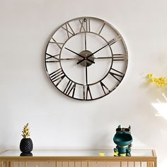 a large clock mounted to the side of a wall next to a vase with yellow flowers