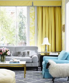 a woman sitting on a couch in a living room with yellow drapes and curtains