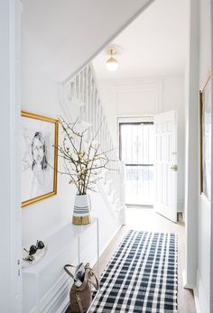 an image of a hallway with white walls and black and white rug on the floor