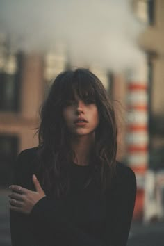 a woman with long hair standing in the street