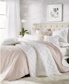 a white bed with pink comforter and pillows