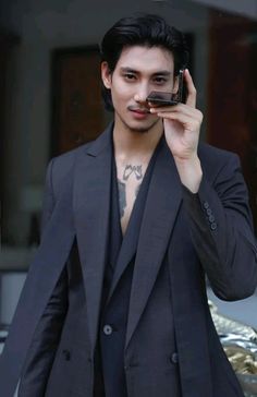 a man in a suit holding a cell phone up to his face and looking at the camera