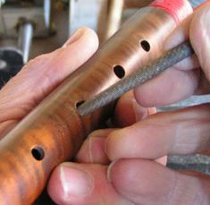 a person holding a metal object with holes in it's center and two hands