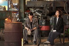 two people sitting on chairs in an industrial setting