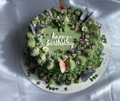 a green birthday cake decorated with butterflies and flowers