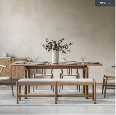 a wooden table with chairs and a vase filled with flowers on it's side